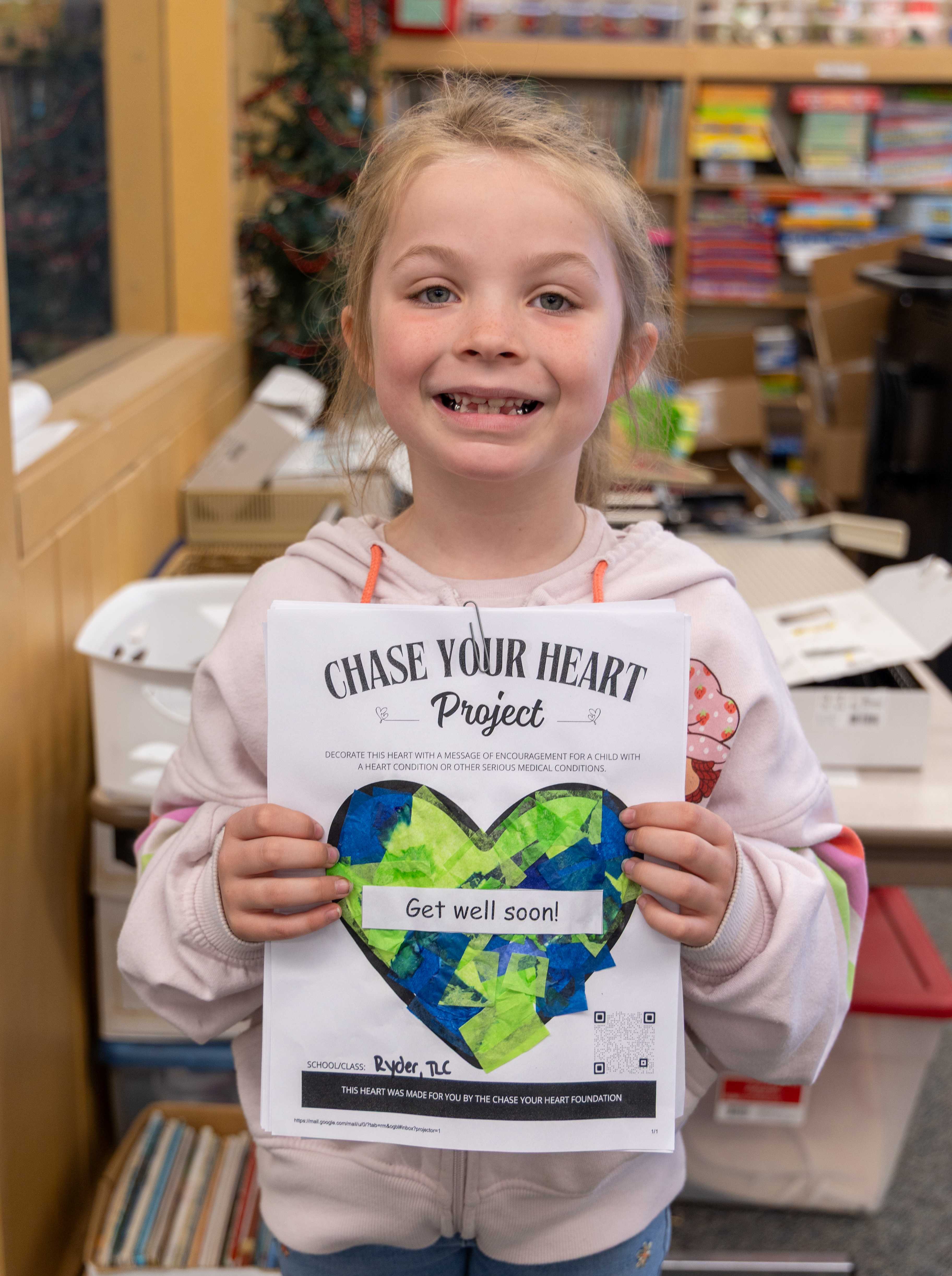 A student holds a designed heart that says "Get well soon!".